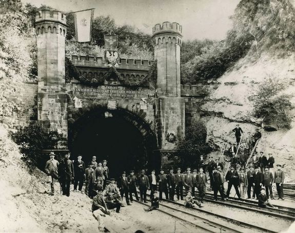 schwarz-weiß Bild mit Menschen vor einem Tunneleingang