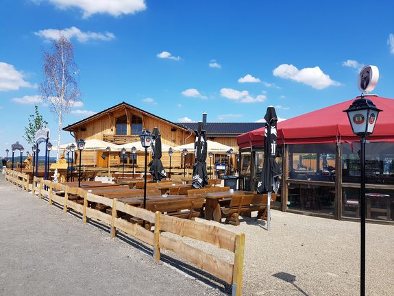 Bierbänke und Tische vor einer Holzhütte